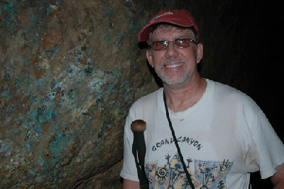 Dennis stands next to a mineral-encrusted wall