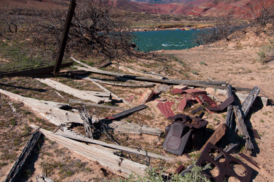 The remains of the old miners' cabin at Basalt Creek delta. Notice the river party stopped along the south side of the Colorado River in the distance