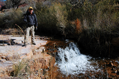 Dennis stands next to a small water fall in Clear Creek